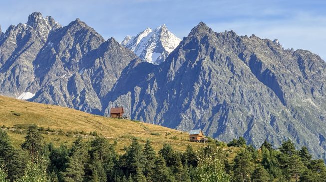 Pemandangan Pegunungan Kaukasus dengan hamparan perbukitan dan dua pondok kayu di kawasan Svaneti, Georgia, Minggu (27/9/2026). [Suara.com/Rizka Chaerani]