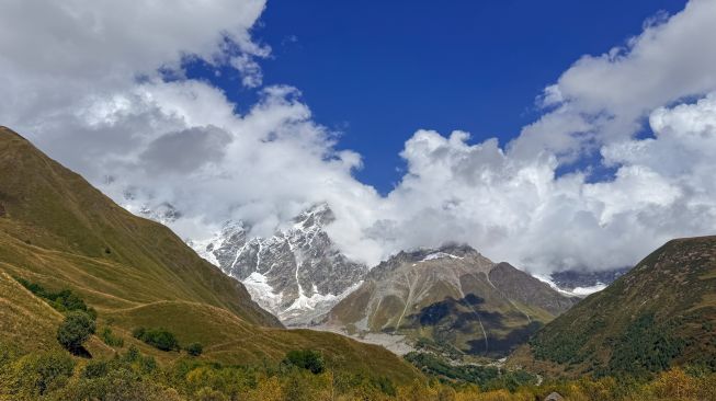Pemandangan Pegunungan Kaukasus dengan puncak bersalju yang diselimuti awan di wilayah Svaneti, Georgia, Minggu (27/9/2026). [Suara.com/Rizka Chaerani]