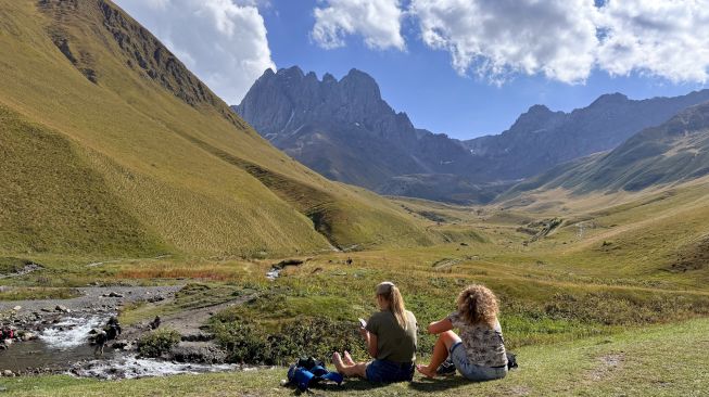Wisatawan menikmati pemandangan Pegunungan Kaukasus dan aliran sungai di kawasan pegunungan Svaneti, Georgia, Minggu (27/9/2026). [Suara.com/Rizka Chaerani]