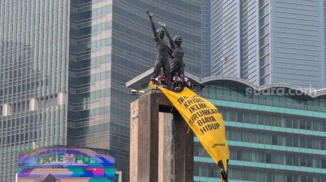 Sejumlah aktivis Greenpeace Indonesia nekat memanjat dan bertahan di puncak Monumen Selamat Datang, Bundaran Hotel Indonesia, Jakarta Pusat, pada Selasa (20/10/2026). (Suara.com/Adiyoga)