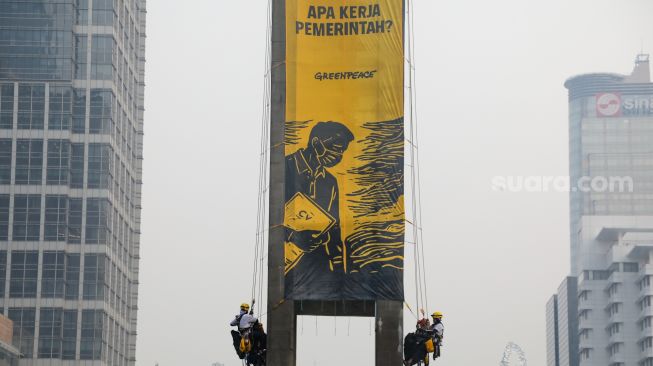 Sejumlah aktifis Greenpeace membentangkan spanduk yang bertema krisis iklim di Bundaran HI, Jakarta, Selasa (20/10/2026). [Suara.com/Alfian Winanto]
