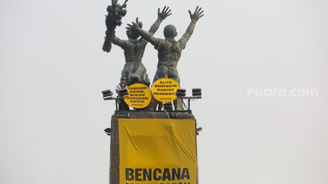 Sejumlah aktifis Greenpeace membentangkan spanduk yang bertema krisis iklim di Bundaran HI, Jakarta, Selasa (20/10/2026). [Suara.com/Alfian Winanto]

