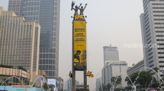 Sejumlah aktifis Greenpeace membentangkan spanduk yang bertema krisis iklim di Bundaran HI, Jakarta, Selasa (20/10/2026). [Suara.com/Alfian Winanto]
