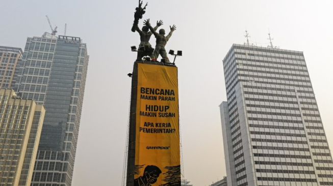 Sejumlah ktivis Greenpeace Indonesia membentangkan dua spanduk raksasa dari puncak Patung Selamat Datang di Bundaran Hotel Indonesia, Jakarta Pusat, Selasa (20/10/2026). Spanduk itu berisi tulisan protes terhadap pemerintahan Prabowo-Subianto yang membiarkan krisis ekologi serta krisis ekonomi. [Odi Putera/Greenpeace]