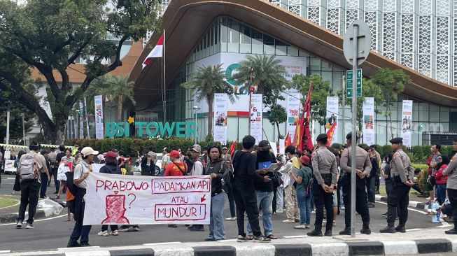 Peserta aksi demo di kawasan Patung Kuda, Jakarta Pusat, Sabtu (24/10/2026), membentangkan spanduk mendesak Presiden Prabowo Subianto untuk segera menyelesaikan persoalan karhutla.
