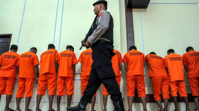 Polisi berjaga di belakang tersangka pencurian kendaraan bermotor (curanmor) saat pengungkapan curanmor di Polres Lhokseumawe, Aceh, Senin (26/10/2026). [ANTARA FOTO/Rahmad/agr]

