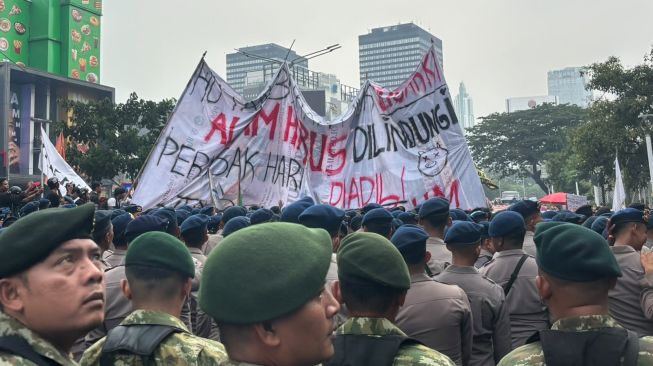 Spanduk raksasa bertuliskan kritik soal kebakaran hutan dan lahan (Karhutla) dibentangkan mahasiswa saat melakukan aksi di depan Plaza UOB, Dukuh Atas. [Suara.com/Faqih]