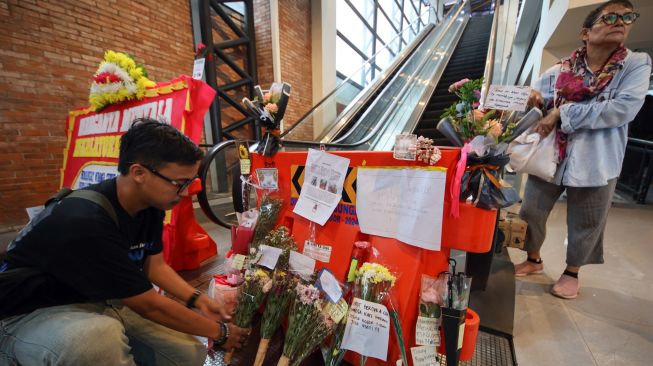 Seorang penumpang kereta melakukan aksi di depan bunga duka cita sebagai bentuk protes atas kerusakan eskalator di Sky Bridge Stasiun Bojonggede, Kabupaten Bogor, Jawa Barat, Rabu (28/10/2026). [ANTARA FOTO/ Yulius Satria Wijaya/kye]
