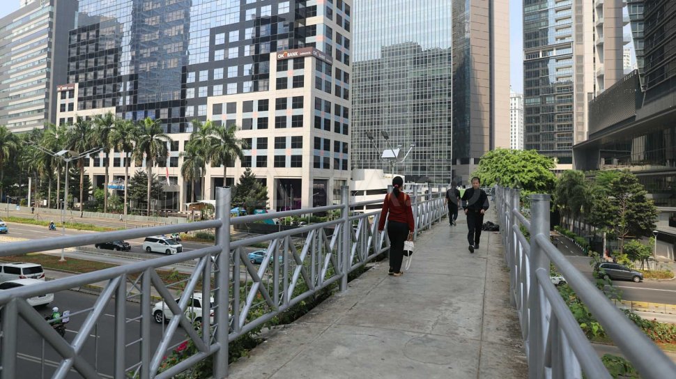 Pejalan kaki melintas di Jembatan Penyeberangan Orang (JPO) tanpa atap di Jalan Sudirman, Jakarta Pusat, Rabu (6/11). [Suara.com/Arya Manggala]
