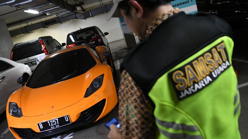 Petugas Samsat Jakarta Utara mengecek pajak sebuah mobil mewah saat razia supervisi pencegahan pajak mobil mewah di Apartemen Regatta, Jakarta Utara di Jakarta, Kamis (5/12). [ANTARA FOTO/M Risyal Hidayat]