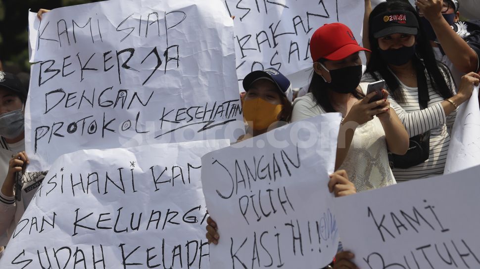 Sejumlah massa yang tergabung dalam Asosiasi Pengusaha Hiburan Jakarta (Asphija) membentangkan poster saat melakukan aksi unjuk rasa di depan Balai Kota DKI Jakarta, Selasa (21/7/2020). [Suara.com/Angga Budhiyanto] 