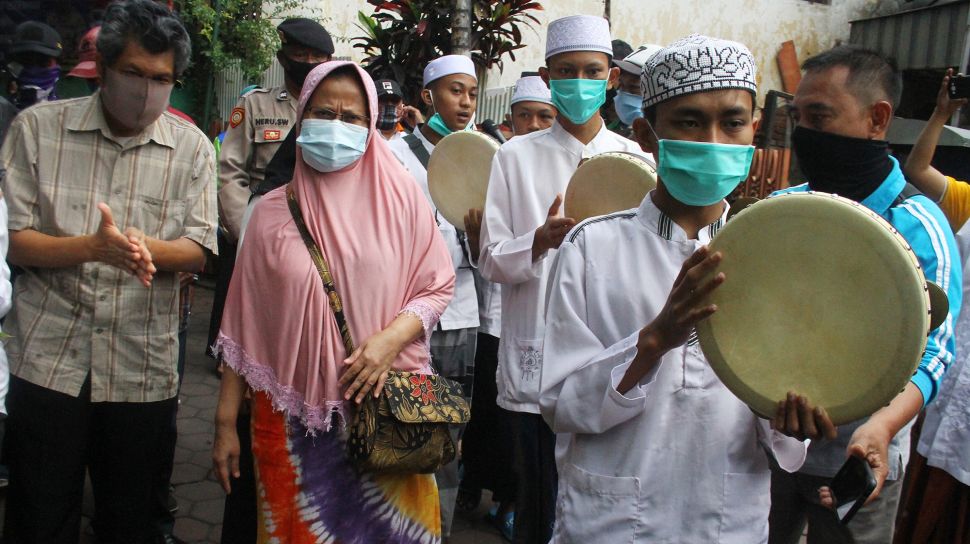 Warga menyambut pasien COVID-19 yang dinyatakan sembuh, Sukati (dua dari kiri) dan Hartoyo (kiri) dengan maukhid atau hadrah di depan rumahnya di Kiduldalem, Malang, Jawa Timur, Rabu (22/7/2020).  [ANTARA FOTO/Ari Bowo Sucipto]