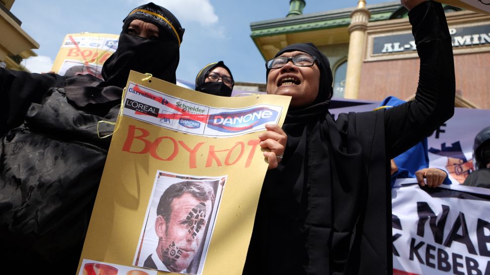 Pengunjuk rasa memegang poster bergambar Presiden Prancis Emmanuel Macron dan istrinya Brigitte Macron saat menggelar aksi boikot produk Prancis di Medan, Sumatera Utara, Jumat (30/10/2020). [ANTARA FOTO/Irsan Mulyadi]
