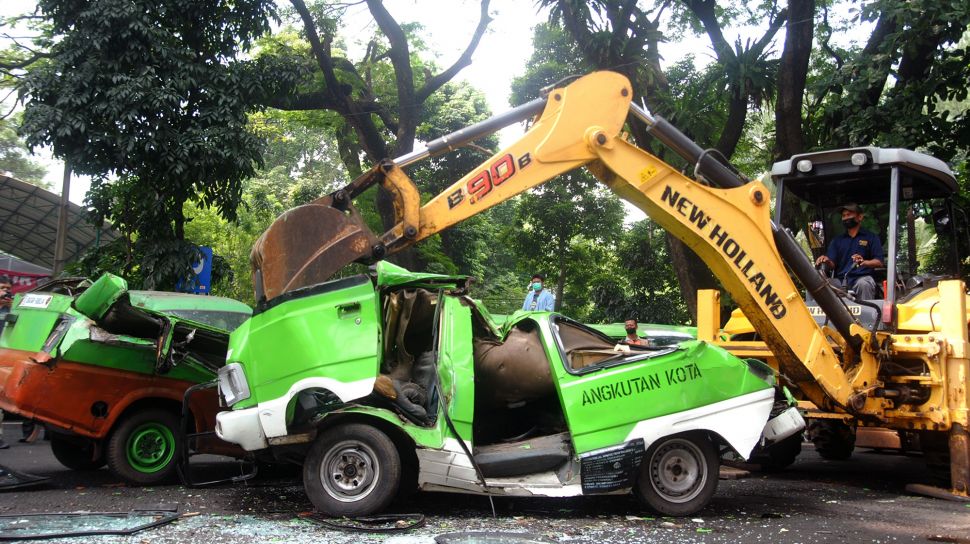 Petugas mengoperasikan alat berat untuk menghancurkan mobil angkutan kota (angkot) di halaman GOR Pajajaran, Kota Bogor, Jawa Barat, Senin (1/11/2021).  ANTARA FOTO/Arif Firmansyah