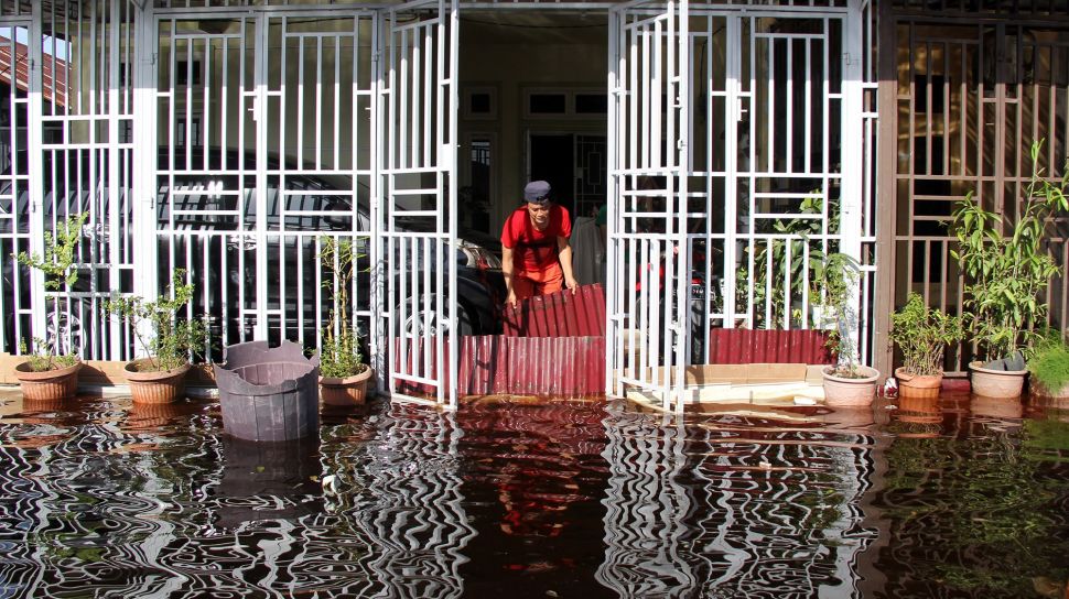 Seorang warga membuat tanggul sementara untuk mencegah air banjir rob masuk ke dalam rumahnya di Dumai, Riau, Sabtu (6/11/2021). ANTARA FOTO/Aswaddy Hamid