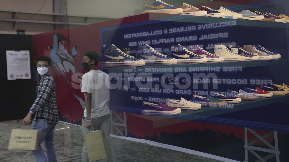 Refleksi pengunjung mengamati produk yang ditawarkan pada acara Urban Sneaker Society 2021 di Jakarta Convention Center, Senayan, Jakarta, Minggu (5/12/2021). [Suara.com/Angga Budhiyanto]