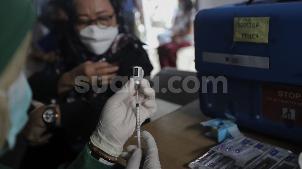 Vaksinator bersiap menyuntikkan vaksin COVID-19 dosis ketiga kepada warga saat vaksinasi booster COVID-19 di Puskesmas Kecamatan Kramat Jati, Jakarta, Rabu (12/1/2022). [Suara.com/Angga Budhiyanto]
