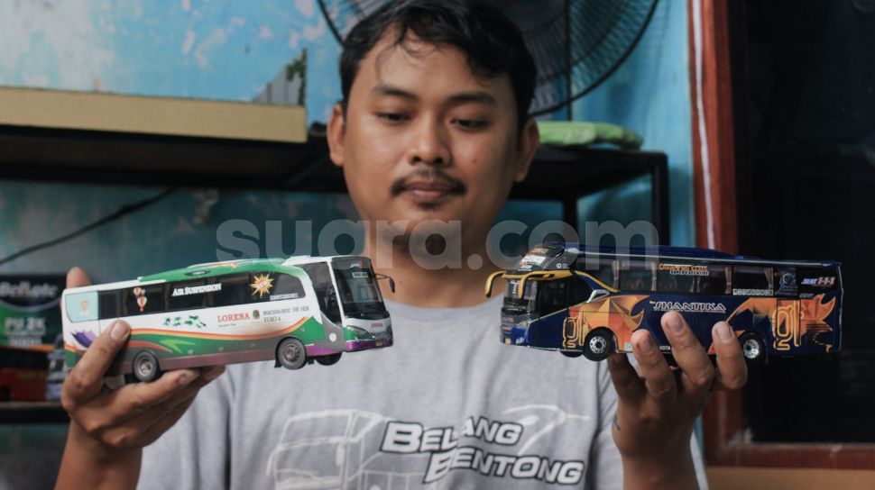Andy Kunaryo (34) menunjukkan miniatur bus buatannya di Workshop Belang Bentong, Limo, Depok, Jawa Barat, Senin (17/1/2022). [Suara.com/Septian]