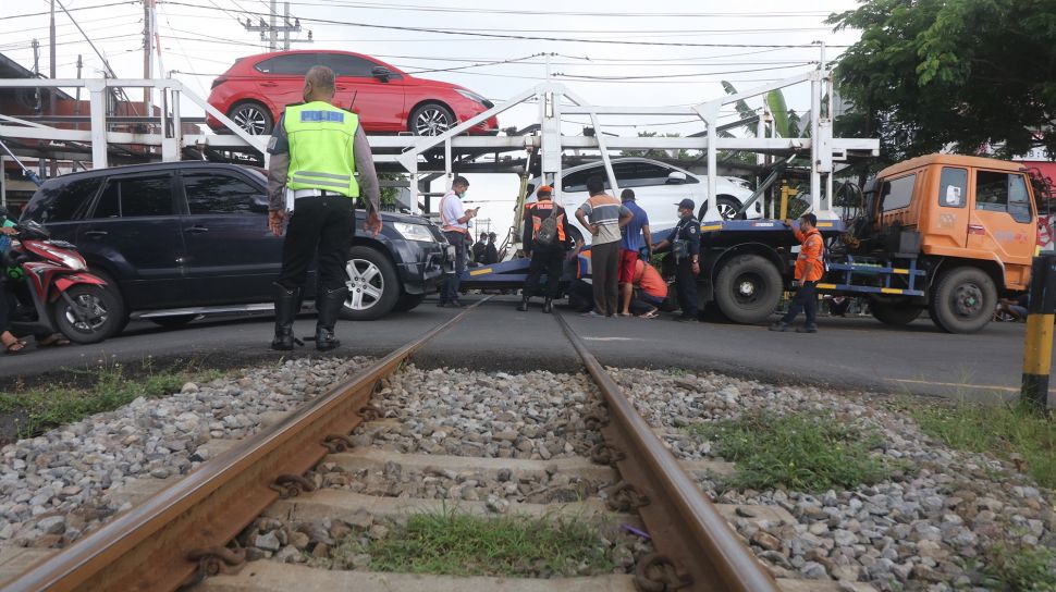 Petugas mengevakuasi truk yang tersangkut perlintasan kereta api di Kelurahan Balowerti, Kota Kediri, Jawa Timur, Selasa (18/1/2022).  ANTARA FOTO/Prasetia Fauzani