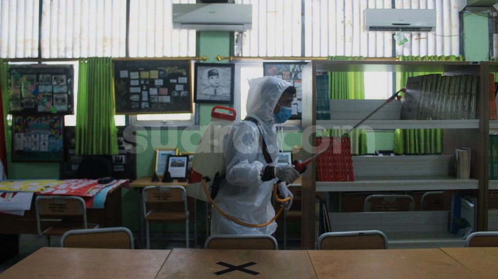 Petugas Palang Merah Indonesia (PMI) menyemprotkan cairan disinfektan di SMA Negeri 66 Jakarta, Jumat (28/1/2022). [Suara.com/Septian]