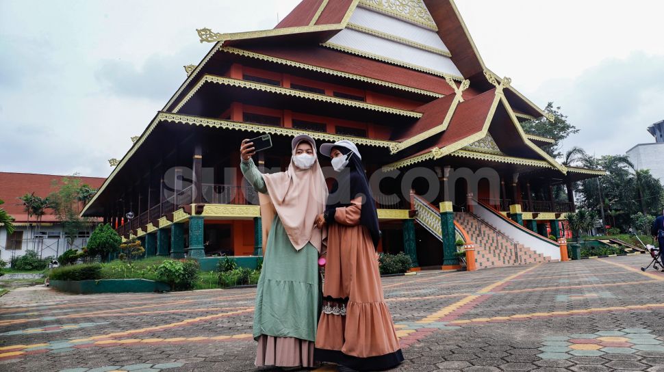 Pengunjung beswafoto saat mengunjungi Anjungan Riau di Taman Mini Indonesia Indah, Jakarta Timur, Rabu (4/5/2022). [Suara.com/Alfian Winanto]