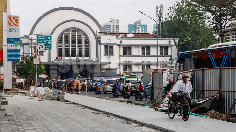 Warga berjalan di jalur pedestrian yang masih dalam tahap revitalisasi di kawasan Kota Tua, Jakarta Barat, Kamis (19/5/2022). [Suara.com/Alfian Winanto]