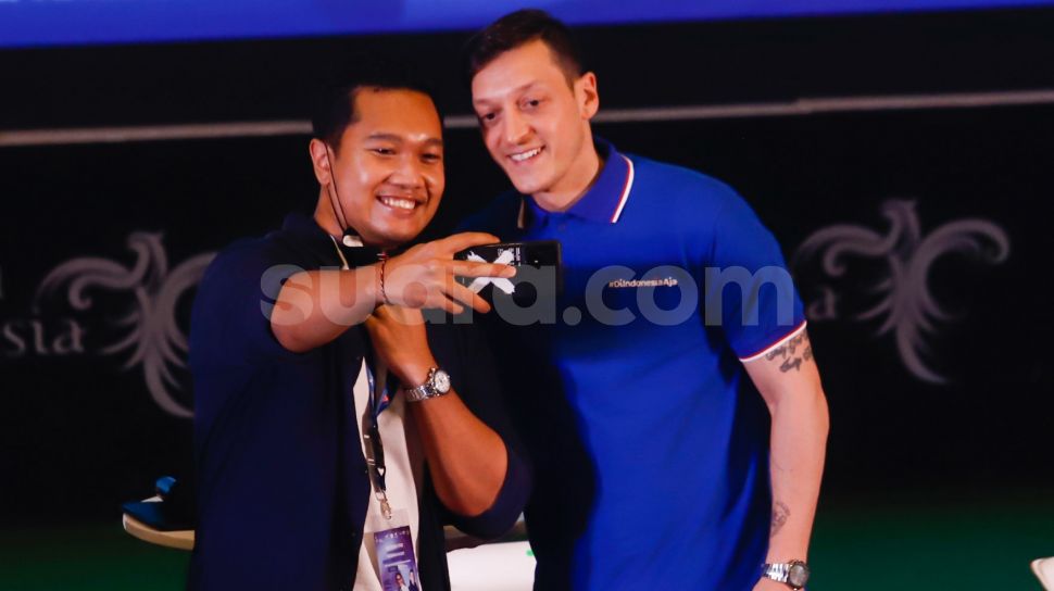 Pesepakbola Mesut Ozil berswafoto dengan fans dalam konferensi pers di Kementerian Pariwisata, Ekonomi dan Kreatif (Kemenparekraf), Jakarta Pusat, Rabu (25/5/2022). [Suara.com/Alfian Winanto]