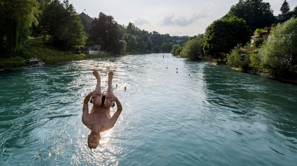 Seorang pemuda melompat ke sungai Aare pada 21 Juni 2017 di Bern, Swiss. [AFP Photo]


