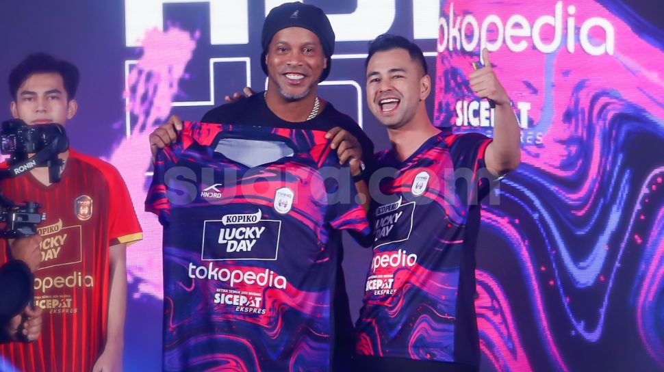 Legenda Sepak Bola Brazil, Ronaldinho (kiri) bersama Chairman RANS Nusantara FC, Raffi Ahmad (kanan) menunjukkan jersey baru untuk musim 2022-2023 di Jakarta, Jum&#039;at (24/6/2022). [Suara.com/Alfian Winanto]
