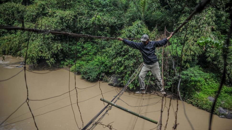 Warga menyeberangi sungai menggunakan jembatan kawat besi di Desa Salamnunggal, Kecamatan Cibeber, Kabupaten Cianjur, Jawa Barat, Sabtu (25/6/2022). [ANTARA FOTO/Raisan Al Farisi/rwa]