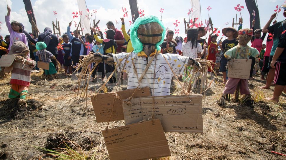 Sejumlah anak memasang karton berisi tulisan harapan pada orang-orangan sawah berbahan jerami dalam Festival Anak Sawah di kawasan persawahan Kampung Lali Gadget (KLG), Desa Pagerngumbuk, Wonoayu, Sidoarjo, Jawa Timur, Minggu (3/7/2022). [ANTARA FOTO/Umarul Faruq/nym]