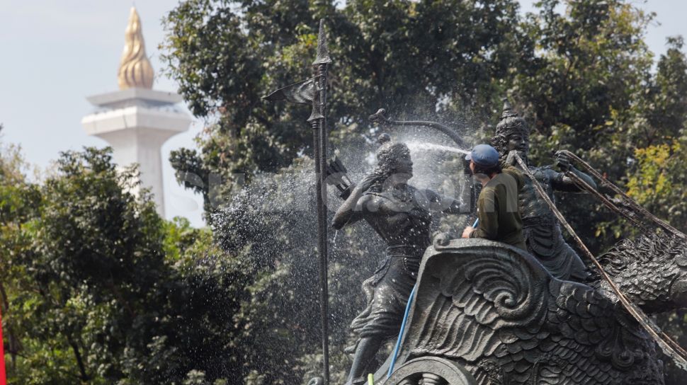 Pekerja membersihkan patung Arjuna Wijaya atau yang lebih dikenal sebagai patung kuda di jalan Medan Merdeka Barat, Jakarta Barat, Selasa (9/8/2022). [Suara.com/Alfian Winanto]