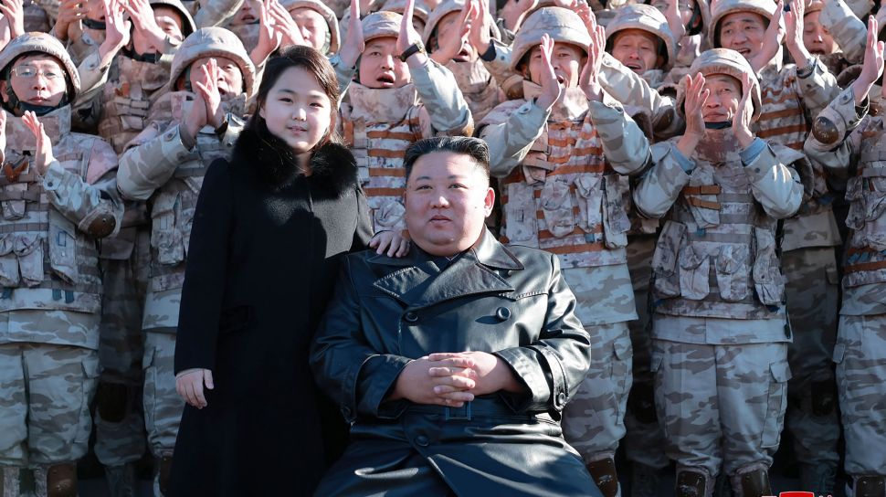 Pemimpin Korea Utara, Kim Jong Un dan putrinya menghadiri sesi foto dengan para ilmuwan, insinyur,  pejabat militer dan para pekerja di pabrik amunisi yang berkontribusi dalam uji coba rudal balistik antarbenua (ICBM) Hwasong-17 di lokasi rahasia, dalam foto tak bertanggal yang rilis pada Minggu (27/11/2022). [KCNA VIA KNS / AFP]