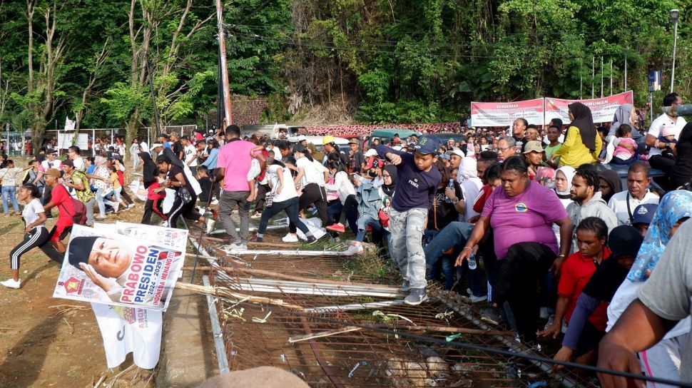 Sejumlah peserta melewati pagar yang roboh saat mengikuti Jalan Sehat Prabowo di Lapangan Karang PTC Entrop, Kota Jayapura, Papua, Rabu (22/3/2023).  [ANTARA FOTO/Sakti Karuru].