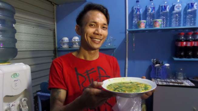 Penyanyi Norman Kamaru saat menyiapkan hidangan Bubur Manado. [Suara.com/Ismail] 