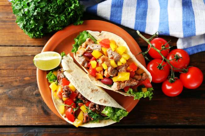 Homemade beef burritos with vegetables on plate, on wooden background