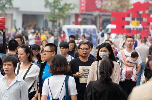 BEIJING, CHINA - SEPTEMBER 25, 2016: A woman using face mask is seen among a crowd of people at Wangfujing Street, which is regarded as one of the busiest shopping streets in Beijing