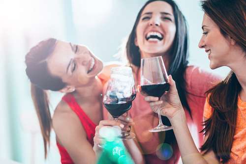 Tiga perempuan sedang bercengkrama sambil menikmati wine. [shutterstock]