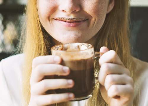 Seorang perempuan sedang menikmati cokelat panas yang tersaji dalam gelas. [shutterstock]