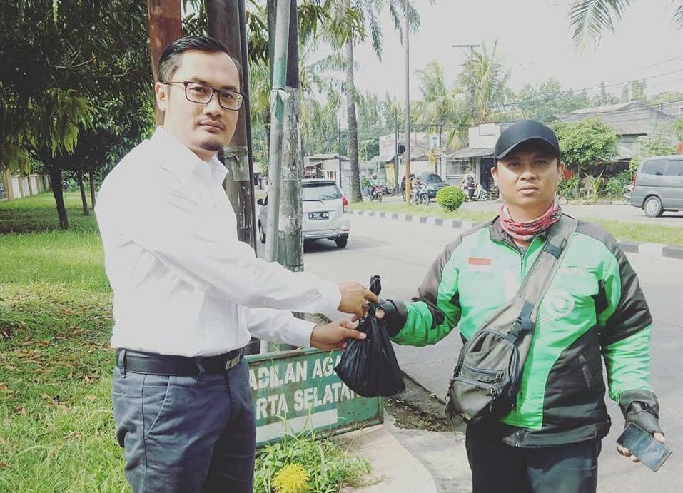 Seorang pengemudi Go-Jek menyerahkan kantung plastik yang diduga berisi bangkai kucing kepada lelaki bernama Antonio di Pengadilan Negeri Jakarta Selatan. [Facebook/Antonio Sri Hendarianto]