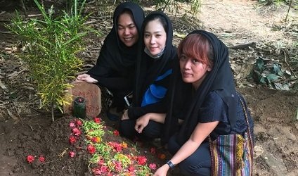 Bunga Zainal (tengah) di depan makam sahabatnya, MUA Eman Suhada alias Emon [Instagram]