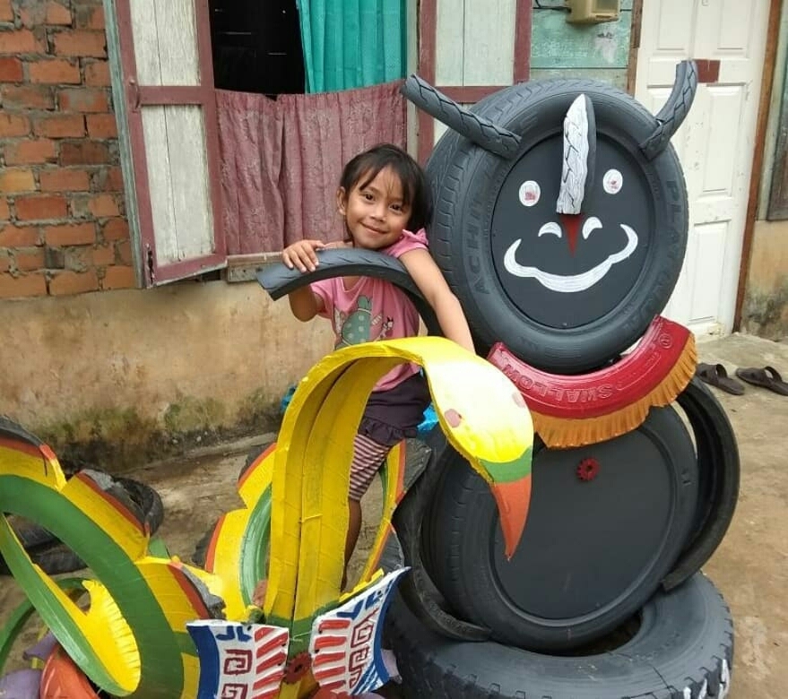 Gadis kecil bernama Nara tersenyum sambil bergelayutan pada sebuah ornamen yang dibuat untuk mensukseskan program kampung Asian Games di Palembang [Suara.com/Andhiko]