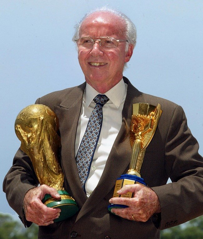 Pemain legendaris Brasil Mario Zagallo berpose dengan trofi Jules Rimet dan Piala Dunia yang pernah dimenangkannya saat masih aktif bermain di timnas Brasil [AFP]