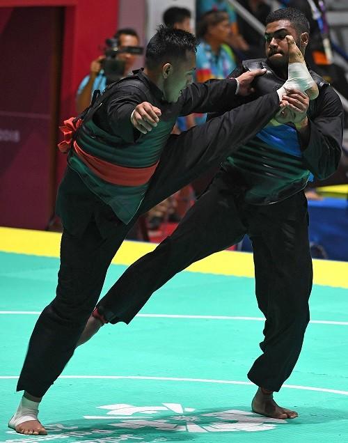 Pesilat Indonesia Eko Febrianto (kiri) menyerang pesilat Singapura Sheik Farhan Sheik Alauddin (kanan) dalam babak perempat final kelas j putra Asian Games 2018 di Padepokan Pencak Silat Taman Mini Indonesia Indah (TMII), Jakarta, Sabtu (25/8). ANTARA FOTO/INASGOC/Melvinas Priananda