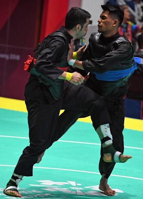 Pesilat Iran Akbar Kiyaniyan (kiri) bertanding melawan pesilat Malaysia Mohd Al Jufferi Jamari (kanan) dalam babak perempat final Kelas E Putra Asian Games 2018 di Padepokan Pencak Silat Taman Mini Indonesia Indah (TMII), Jakarta, Jumat (24/8). ANTARA FOTO/INASGOC/Melvinas Priananda