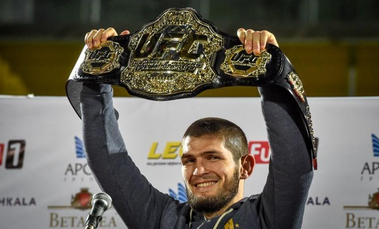 Juara dunia kelas ringan UFC, Khabib Nurmagomedov, memamerkan sabuk juaranya setibanya di Makhachkala, Rusia, Senin (8/10/2018). [AFP/Vasily Maximov]