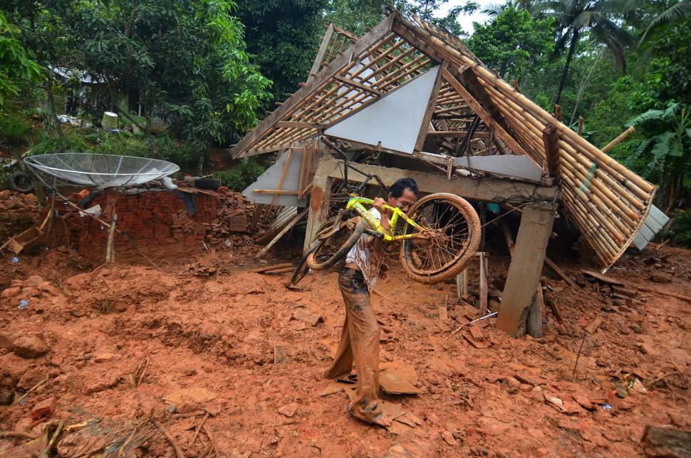 Warga membawa sepeda yang masih bisa diselamatkan di rumahnya yang tertimbun material tanah longsor di Desa Bojongsari, Kabupaten Tasikmalaya, Jawa Barat, Kamis (8/11). [ANTARA FOTO/Adeng Bustomi]