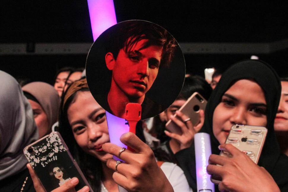 Sejumlah penonton bernyanyi sambil memegang poster penyanyi Amerika Serikat Charlie Puth tampil di ICE BSD, Tangerang, Banten, Jumat (16/11). (Suara.com/Fakhri Hermansyah)