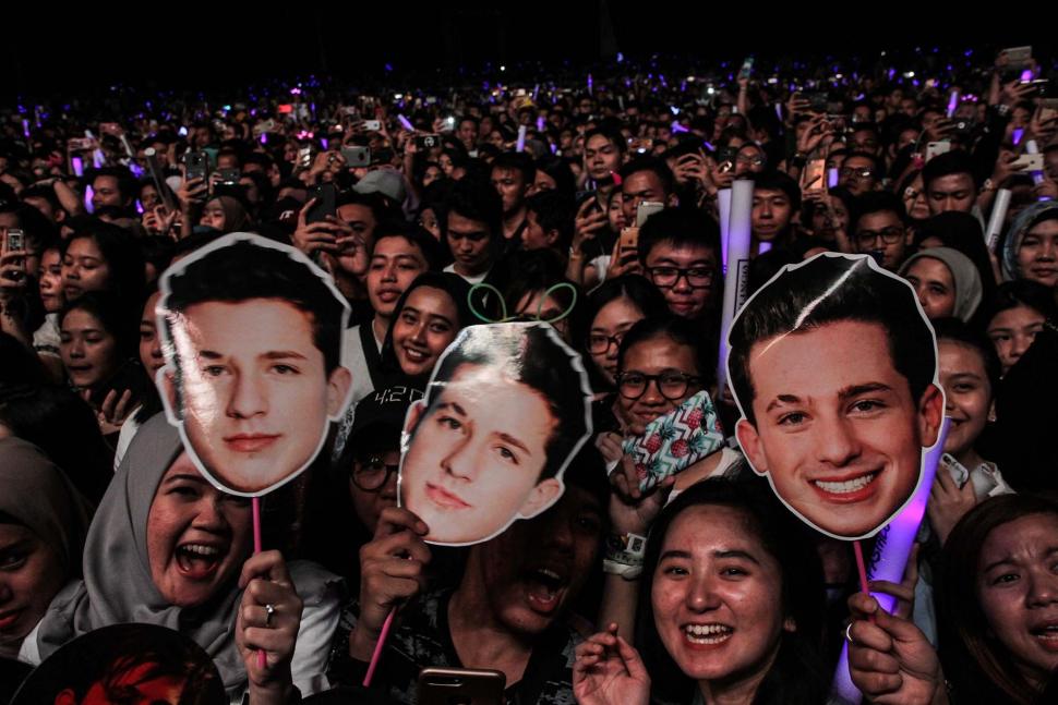 Sejumlah penonton bernyanyi sambil memegang poster penyanyi Amerika Serikat Charlie Puth tampil di ICE BSD, Tangerang, Banten, Jumat (16/11). (Suara.com/Fakhri Hermansyah)