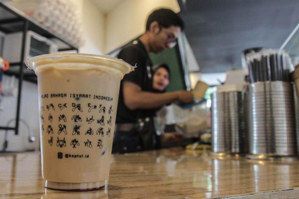 Gelas plastik Cafe Koptul (Kopi Tuli) yang bergambar tutorial bahasa Isyarat di kawasan Duren Tiga, Pancoran, Jakarta Selatan, Kamis (29/11). (Suara.com/Fakhri Hermansyah)